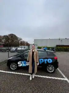 Voertuig met rijschoollogo en tevreden leerling na slagen.